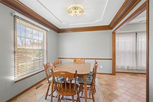 dining room with a textured ceiling, light tile patterned floors, baseboards, and ornamental molding