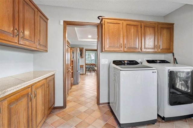 laundry room with washer and clothes dryer, cabinet space, a textured ceiling, and baseboards