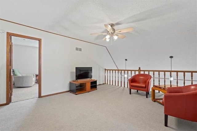 sitting room featuring visible vents, a textured ceiling, carpet flooring, baseboards, and ceiling fan