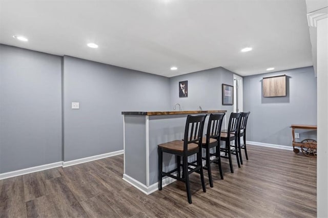 bar featuring recessed lighting, baseboards, wet bar, and dark wood-style floors