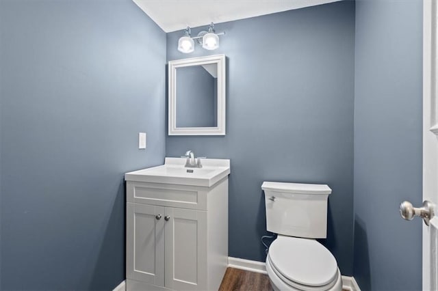 bathroom with vanity, toilet, wood finished floors, and baseboards