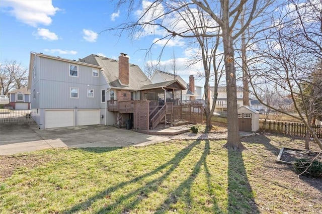 rear view of house with stairway, fence, an attached garage, an outdoor structure, and a storage unit