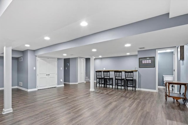 finished below grade area with a bar, recessed lighting, wood finished floors, and baseboards