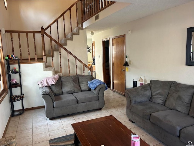 living area with light tile patterned floors, visible vents, stairs, and baseboards