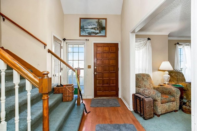 foyer featuring stairs, wood finished floors, baseboards, and ornamental molding