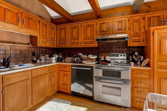 kitchen with under cabinet range hood, light countertops, range with two ovens, dishwashing machine, and a sink