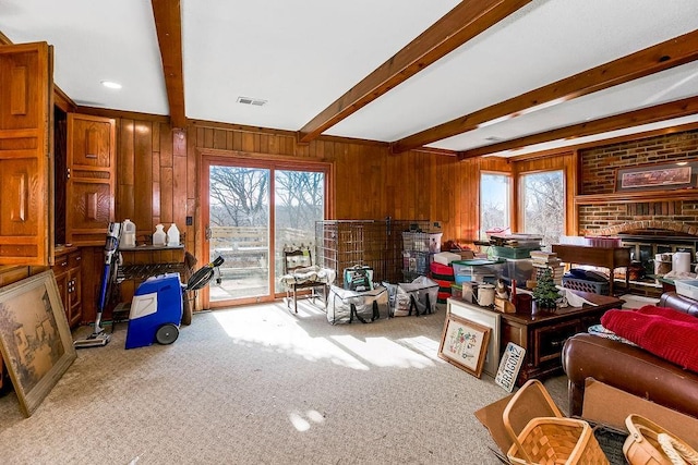 living room featuring beam ceiling, visible vents, wood walls, and carpet