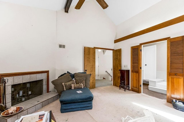 living area with carpet, a ceiling fan, visible vents, high vaulted ceiling, and a tile fireplace