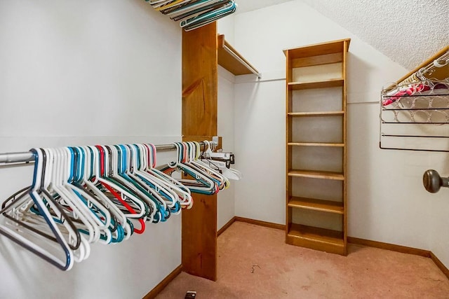 walk in closet with light carpet and lofted ceiling