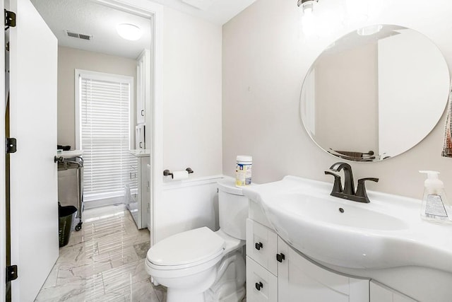 bathroom featuring vanity, toilet, visible vents, and marble finish floor