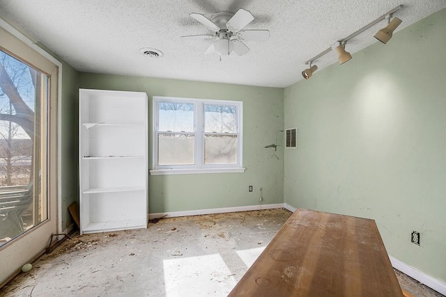 empty room with visible vents, a textured ceiling, and baseboards