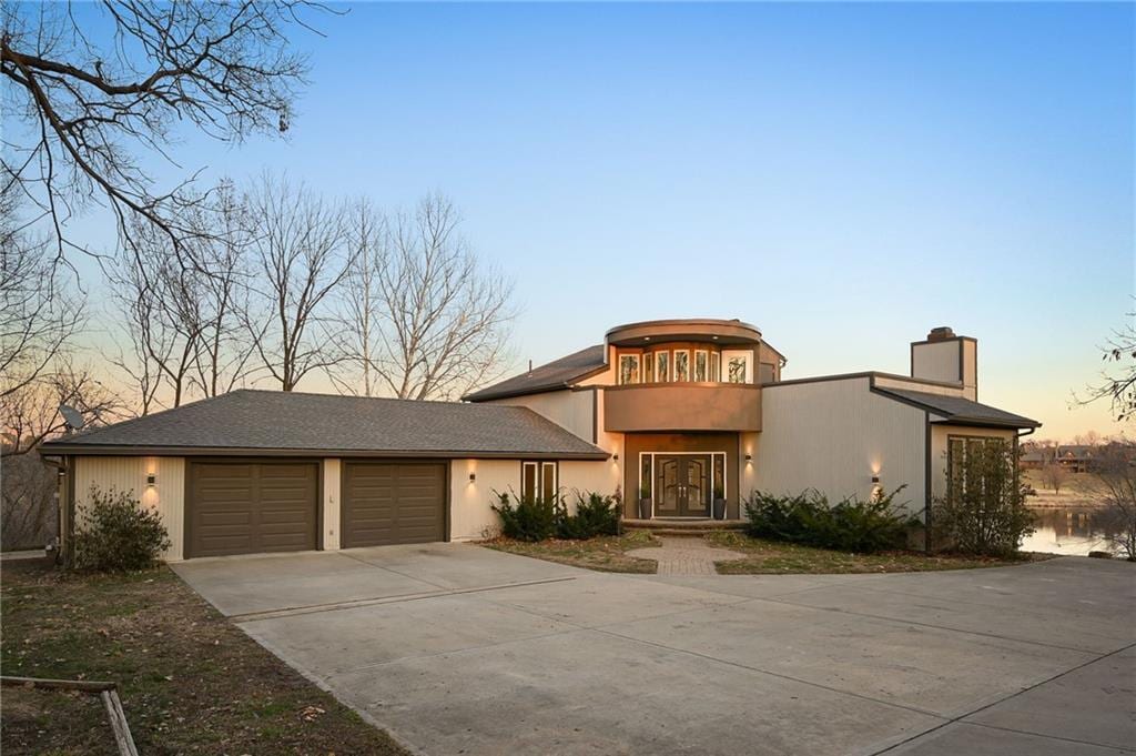 view of front facade featuring a chimney, concrete driveway, and an attached garage