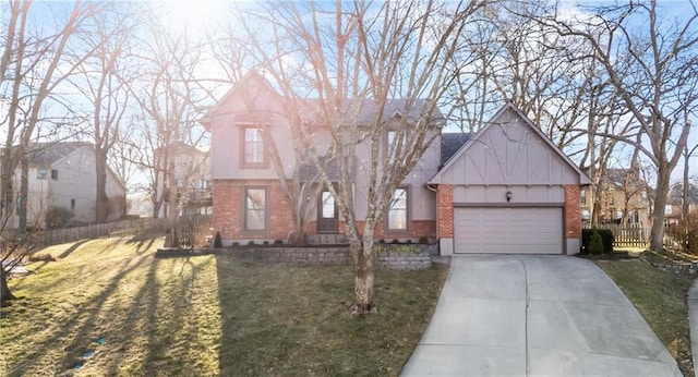 tudor house featuring brick siding, an attached garage, fence, a front yard, and driveway