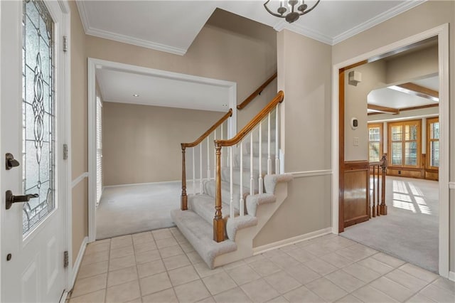 tiled entrance foyer with carpet flooring, stairs, baseboards, and ornamental molding