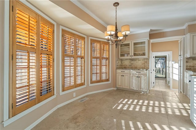 kitchen with decorative backsplash, glass insert cabinets, a notable chandelier, and ornamental molding