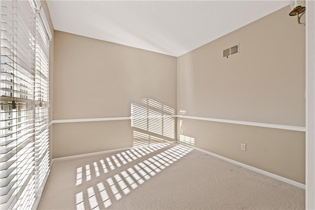 spare room with visible vents, baseboards, lofted ceiling, and carpet floors