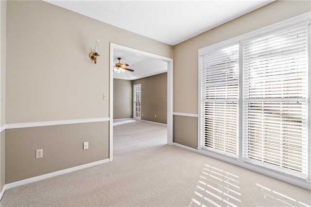 carpeted empty room with baseboards and ceiling fan