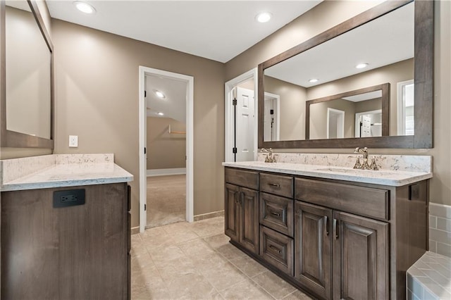 bathroom featuring a sink, baseboards, recessed lighting, and double vanity