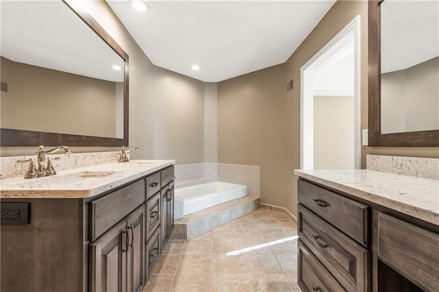 full bath with tile patterned floors, visible vents, a garden tub, a sink, and double vanity