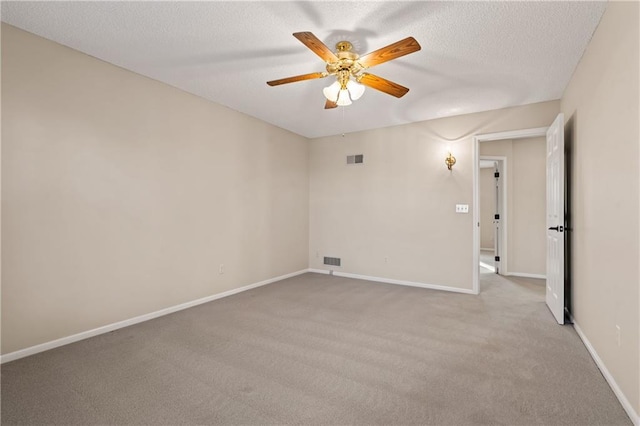 carpeted spare room featuring visible vents, baseboards, a textured ceiling, and ceiling fan