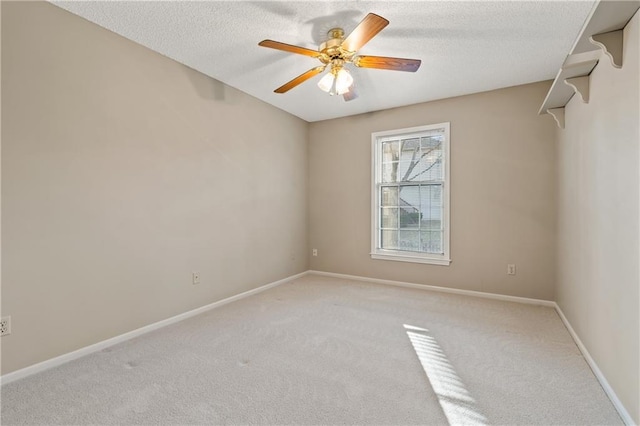 empty room with light colored carpet, baseboards, a textured ceiling, and ceiling fan