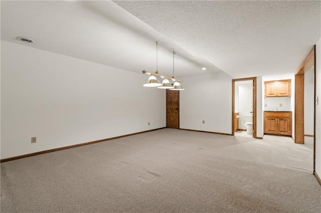 spare room with visible vents, light colored carpet, baseboards, and a textured ceiling