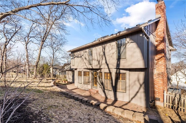 rear view of property with a chimney and fence