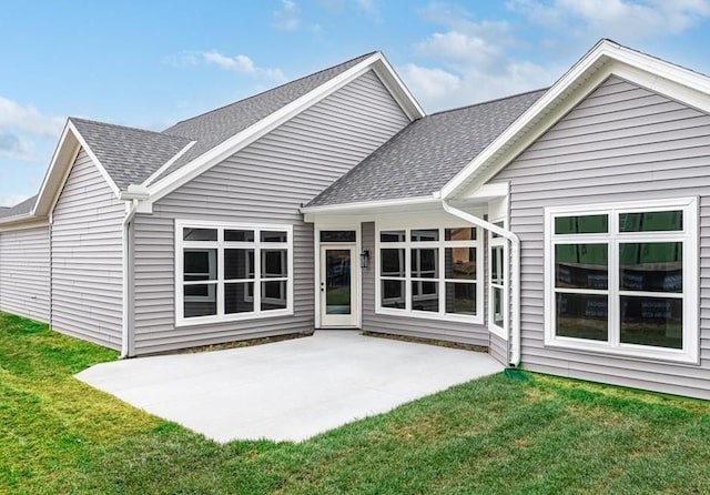 back of house featuring a patio area, a lawn, and a shingled roof