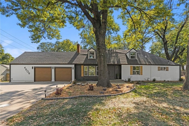 view of front of home featuring a front yard, an attached garage, driveway, and a chimney