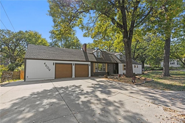 view of front of property with concrete driveway, fence, a garage, and a chimney