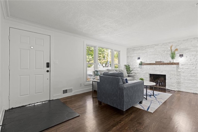 living area featuring visible vents, crown molding, a stone fireplace, wood finished floors, and a textured ceiling