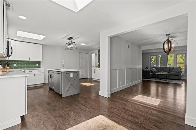 kitchen featuring a skylight, dark wood-style flooring, decorative backsplash, light countertops, and open floor plan