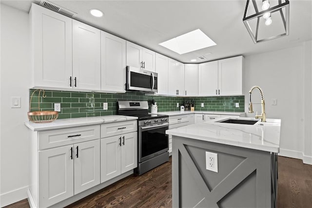 kitchen featuring decorative backsplash, a skylight, dark wood-style floors, and stainless steel appliances