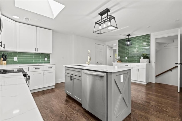 kitchen with a sink, backsplash, dark wood finished floors, a skylight, and dishwasher