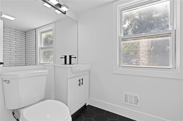 bathroom with vanity, visible vents, baseboards, tile patterned flooring, and toilet