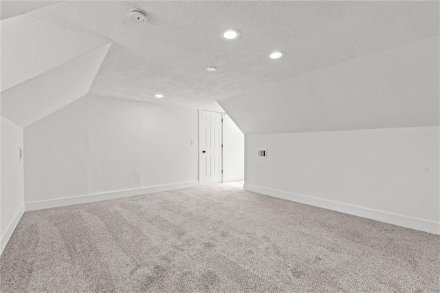 additional living space with lofted ceiling, baseboards, a textured ceiling, and carpet floors