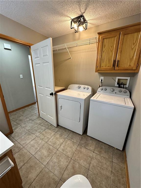 washroom featuring light tile patterned floors, separate washer and dryer, baseboards, and a textured ceiling