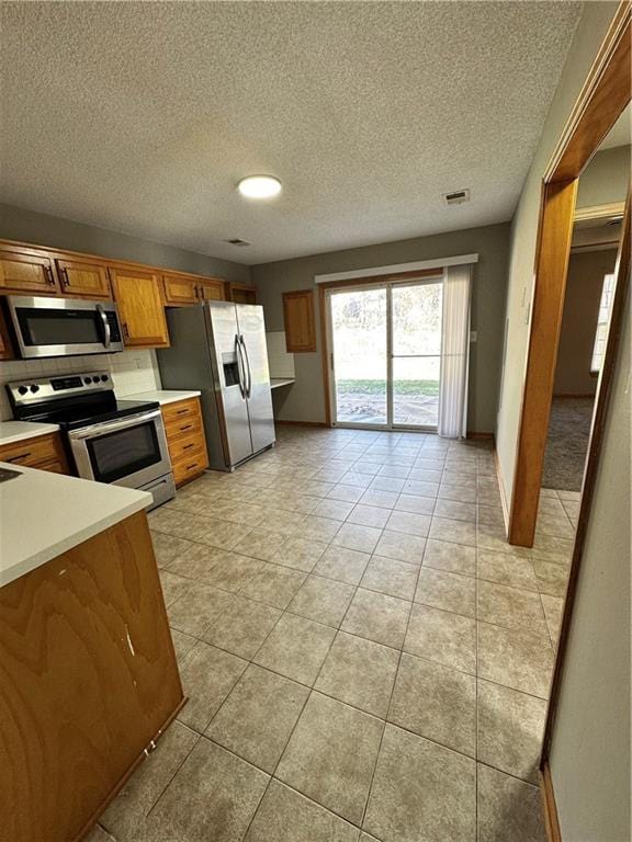 kitchen with visible vents, light countertops, light tile patterned floors, brown cabinets, and appliances with stainless steel finishes