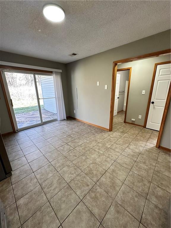 empty room featuring visible vents, baseboards, and a textured ceiling