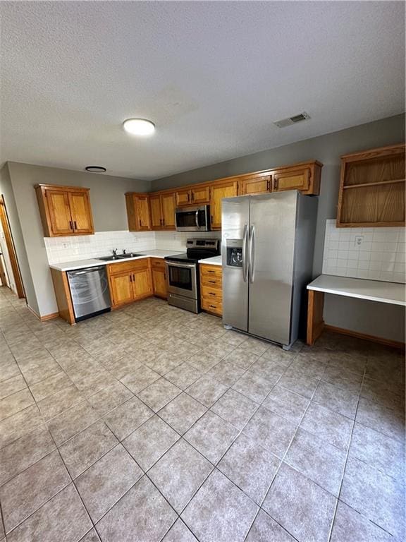 kitchen with visible vents, a sink, light countertops, appliances with stainless steel finishes, and tasteful backsplash