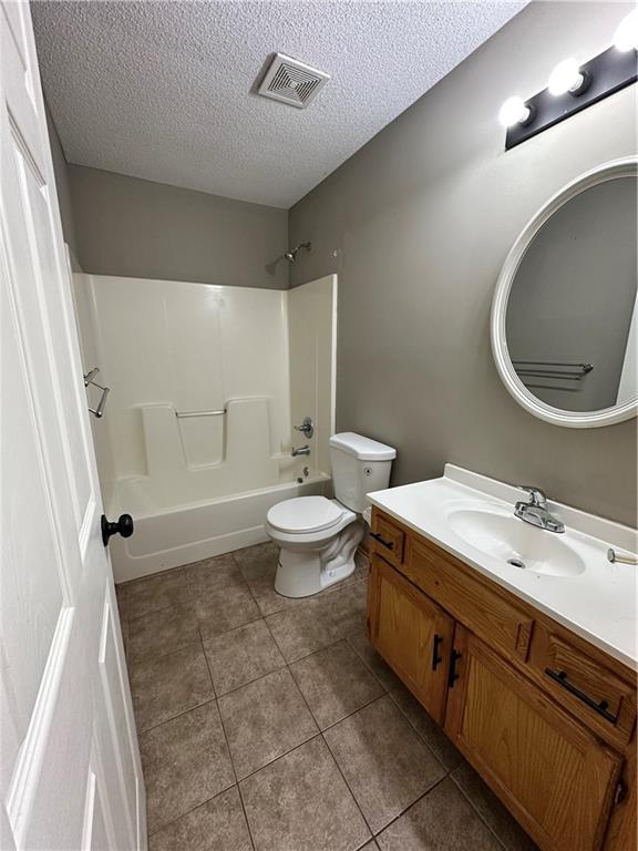 full bath with vanity, washtub / shower combination, visible vents, tile patterned flooring, and toilet