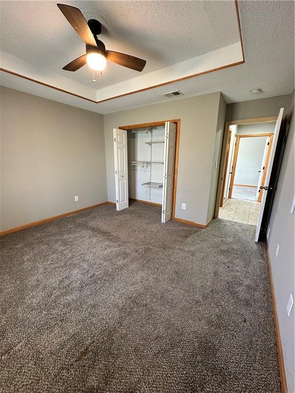 unfurnished bedroom featuring a raised ceiling, baseboards, visible vents, and carpet floors