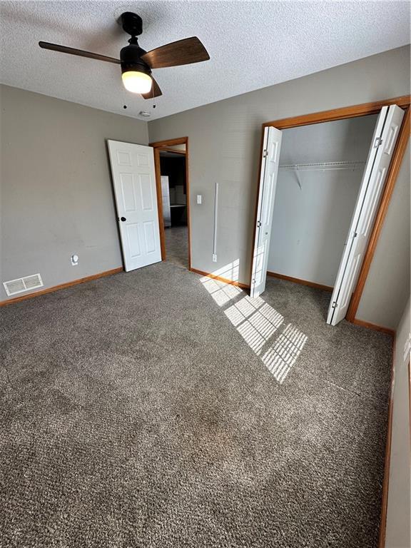 unfurnished bedroom featuring visible vents, carpet, a closet, and a textured ceiling