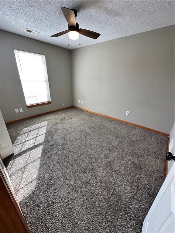 unfurnished room with a ceiling fan, baseboards, visible vents, a textured ceiling, and carpet flooring