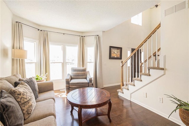 living room featuring visible vents, a textured ceiling, stairs, and baseboards