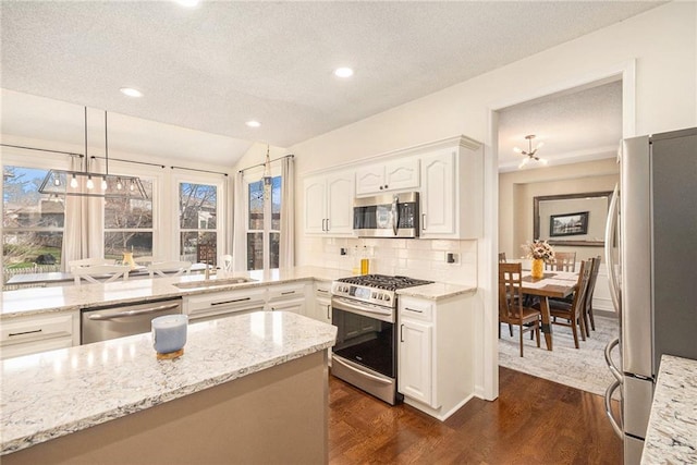 kitchen featuring a sink, light stone counters, tasteful backsplash, dark wood finished floors, and stainless steel appliances
