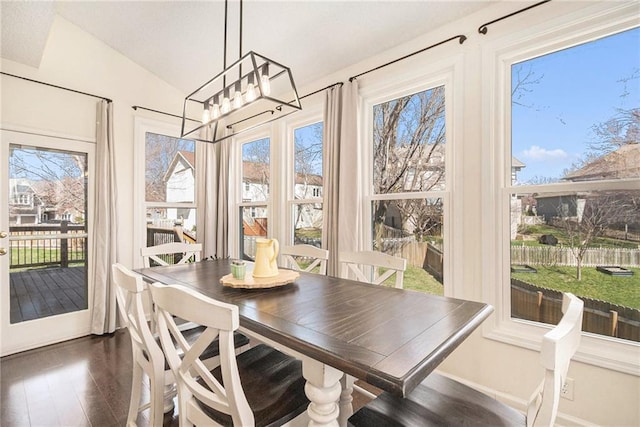 dining area featuring an inviting chandelier, vaulted ceiling, dark wood-style flooring, and a healthy amount of sunlight