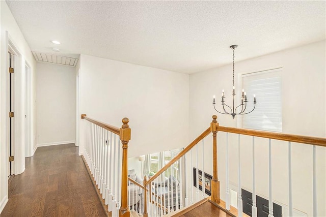 hall featuring an upstairs landing, a notable chandelier, a textured ceiling, and wood finished floors