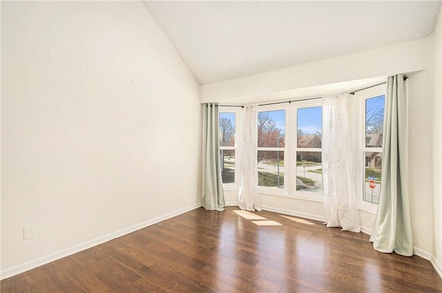 empty room with baseboards, wood finished floors, and vaulted ceiling