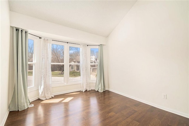 spare room with baseboards, dark wood-type flooring, and vaulted ceiling
